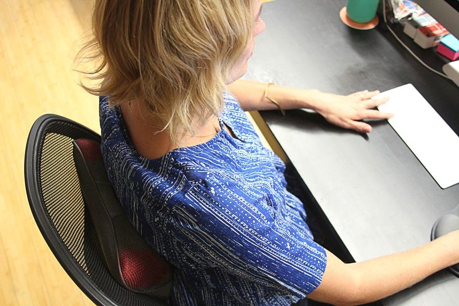 woman using pillow shaped back massager in office chair
